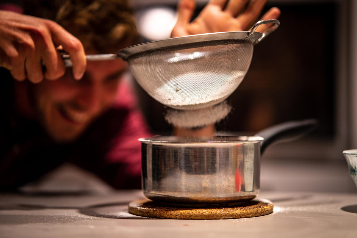 Edouard Henry tamise une préparation au-dessus d'une casserole